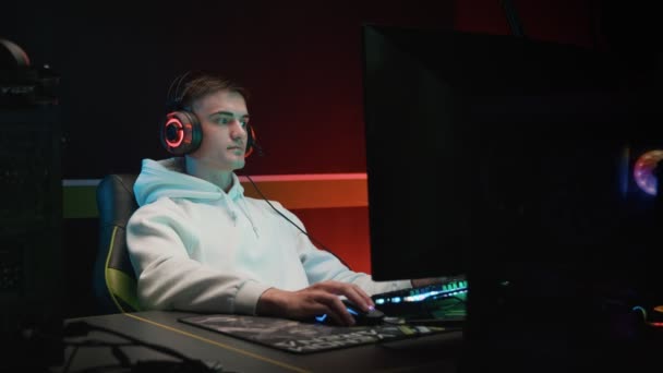 Ein junger Spieler spielt auf einem Computer mit Kopfhörern — Stockvideo