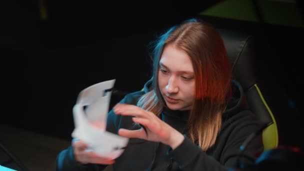 Young gamer girl at the computer puts on a mask and hood close-up — Stock Video