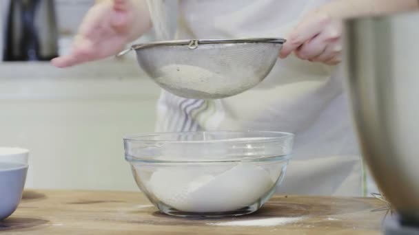 Ein Mädchen in der Küche gießt in Großaufnahme Mehl in eine Glasschüssel — Stockvideo