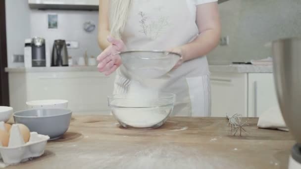 Дівчина на кухні вливає борошно в скляну миску — стокове відео
