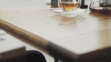 Bir adam masanın altından bir hediye kutusu alır ve bir kafe veya restoranın yakın planında masanın üzerine koyar.