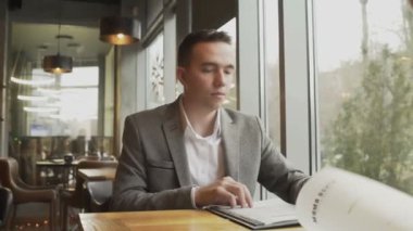 Bir erkek ve bir kadın menüden bir yemek seçiyorlar, pencerenin yanındaki bir kafede karşılıklı oturuyorlar. Hoş bir çiftin randevusu var..