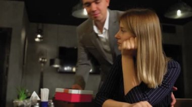 Bir kadın bir kafede masada otururken, bir erkek arkasından bir hediye kutusuyla gelir ve onu bir kadına verir. Kadın hediyeyle mutlu oldu. Kafede ya da restoranda bir randevu.