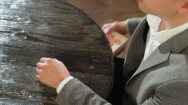 Bir adam masanın altından bir hediye kutusu alır ve bir kafe veya restoranın yakın planında masanın üzerine koyar.
