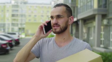 Erkek kurye bir müşteriyi telefonla arar ve teslimat adresini belirtir.