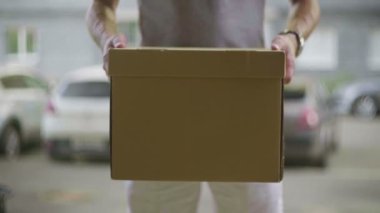 Erkek bir kurye, karton bir kutuya yakından bakar.