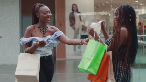 Primer plano de una joven africana le muestra a su amiga qué tipo de cosas compró — Vídeos de Stock