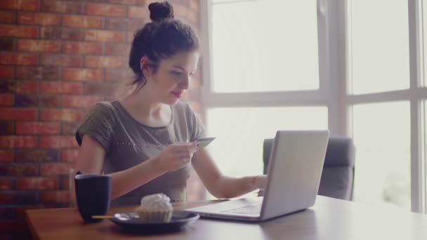 Молодая женщина сидит за компьютером и делает покупки — стоковое видео