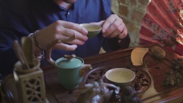 Мужчина пьет зеленый чай из чайного сервиза в чайной комнате — стоковое видео