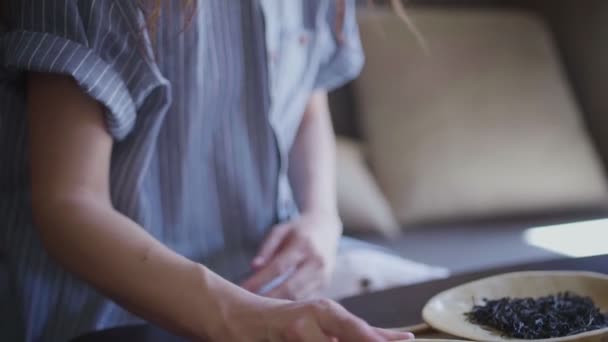 Ein schönes, gelocktes Mädchen nimmt eine hölzerne Schüssel mit Teeblättern und schnüffelt — Stockvideo