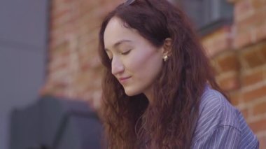 Güzel, kıvırcık saçlı bir kız çay içer ve sokaklarda eğlenir.