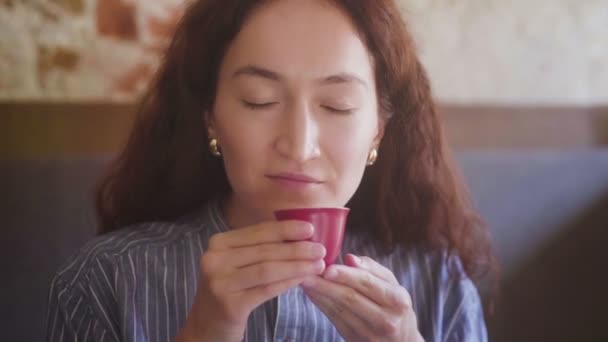 Una hermosa chica de pelo rizado prueba el té y disfruta del sabor — Vídeos de Stock