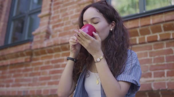 Piękna, kręcone włosy dziewczyna pije herbatę i cieszy się swoim smakiem na ulicy — Wideo stockowe