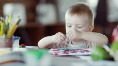 Bir çocuk masada renkli plastiklerle oynuyor.