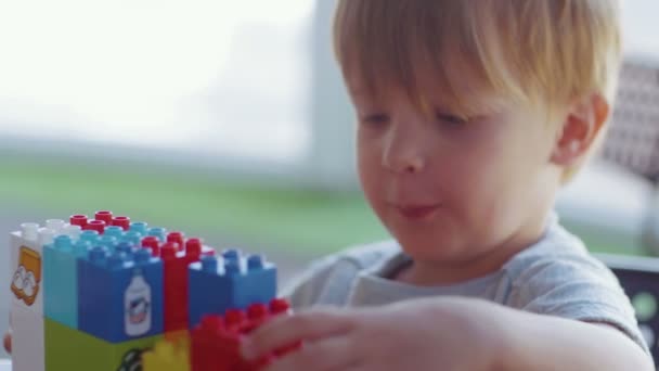 Close-up van een schattig jongetje spelen met een kleurrijke plastic auto. — Stockvideo