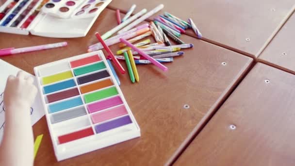 Вид сзади ребенок играет с цветным пластилином за столом — стоковое видео