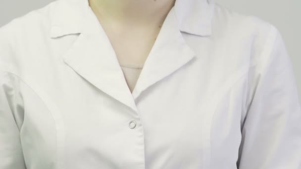 Primer plano de un médico una mujer con una bata médica se pone un estetoscopio en el cuello — Vídeo de stock