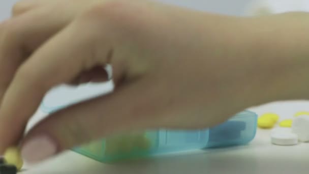 Κοντινό πλάνο ενός πολυβολείου με διαφορετικά δισκία. Τα χέρια ενός ανθρώπου βάζουν χάπια σε ένα κουτί χαπιών. — Αρχείο Βίντεο
