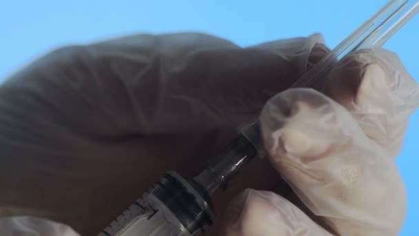 Close-up de uma agulha de uma seringa descartável. Uma mão humana remove a tampa da seringa sobre um fundo azul — Vídeo de Stock