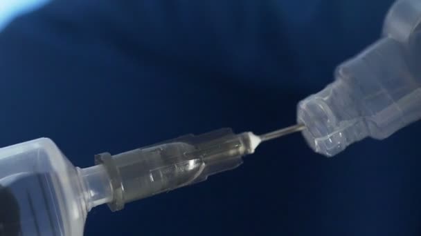 Großaufnahme einer Arzthand bei der Vorbereitung eines Impfstoffes für die Injektion auf blauem Hintergrund — Stockvideo
