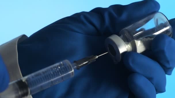 Close-up van een arts die een vaccin maakt voor injectie op een blauwe achtergrond — Stockvideo