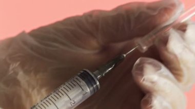 Doktorun elleri kırmızı arka planda aşı için aşı hazırlıyor.
