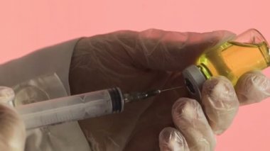 Doktorun elleri kırmızı arka planda aşı için aşı hazırlıyor.