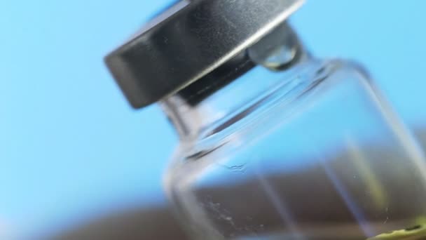 Pendekatan tangan dokter menyiapkan vaksin untuk disuntik dengan latar belakang biru — Stok Video