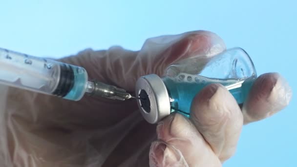 Close-up of a doctors hands preparing a vaccine for injection on a blue background — Stock Video