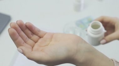 Tanımlanamayan bir kadının, bir hastanın, elinde bir kavanoz hapla eline doldurduğu fotoğrafı.