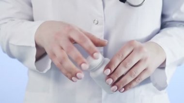 Tanımlanamayan bir kadının, bir doktorun elinde bir kavanoz hapla fotoğrafı.