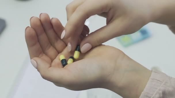 An unrecognizable girl takes pills from her hand and washes them down with water, close-up — Stock Video