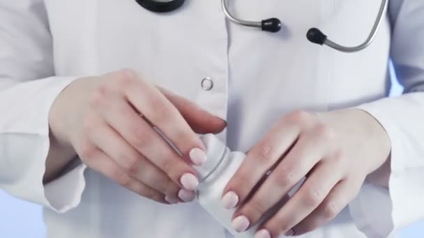 Close-up of an unrecognizable woman, a doctor, holding a jar of pills and throwing it into her hand — Stock Video