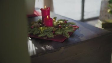 İki kırmızı mum ve bir altın mumu olan ebedi yeşil bir çelenk. Noel arifesinde Hıristiyanların gelenek ve adetleri.