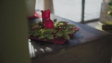 İki kırmızı mum ve bir altın mumu olan ebedi yeşil bir çelenk. Noel arifesinde Hıristiyanların gelenek ve adetleri.