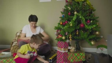 Bir anne ve çocuk güzel bir paket kağıdına hediye koyar. Noel zamanı. Şenlik havası.