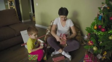 Bir anne ve çocuk güzel bir paket kağıdına hediye koyar. Noel zamanı. Şenlik havası.