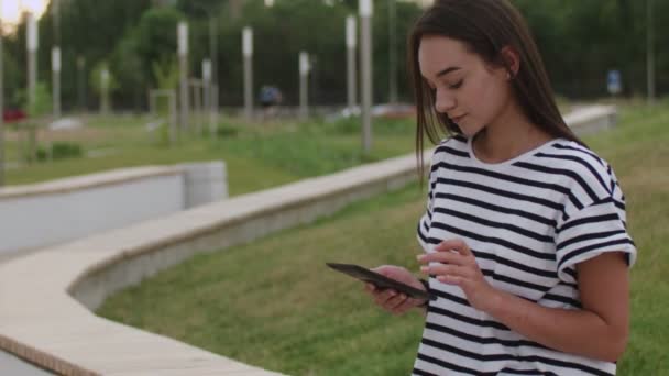 A girl on the street reads an e-book — Stock Video