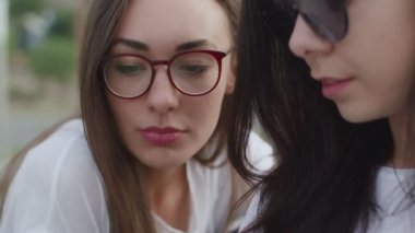 Açık havada iki kız bir e-kitap okudu.