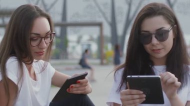Açık havada iki kız bir e-kitap okudu.