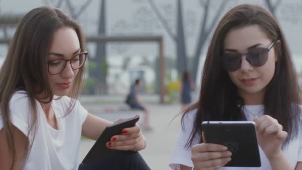 Two girls in the open air read an e-book — Stock Video