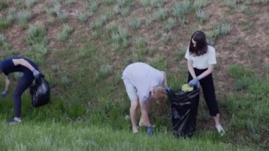 Bir grup öğrenci çöp torbasında çöp topluyor. Plastik kirliliği ve çevresel sorun kavramı. Plastikten doğanın gönüllü temizliği.