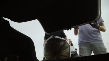 Genç gönüllüler çöp torbalarını arabaya koydu. Plastik kirliliği ve çevresel sorun kavramı. Plastikten doğanın gönüllü temizliği.