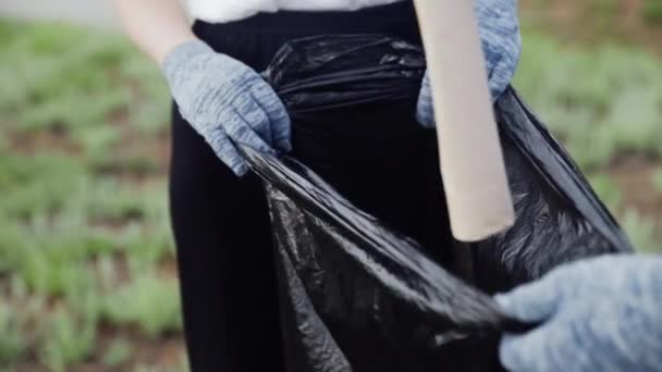 Gros plan des bénévoles ramassent les ordures dans un sac poubelle. Pollution plastique et concept de problème environnemental. Nettoyage volontaire de la nature du plastique. — Video