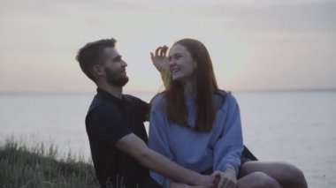 Genç ve güzel bir çift kayalıklarda oturup nehri seyrediyor.