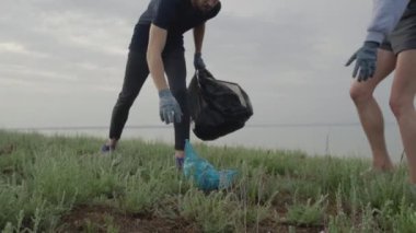 Plajda plastik temizleme ekibi çalışması. Gönüllüler çöp torbasında çöp topluyor. Plastik kirliliği ve çevresel sorun kavramı. Plastikten doğanın gönüllü temizliği.