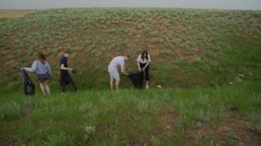 Plajda plastik temizleme ekibi çalışması. Gönüllüler çöp torbasında çöp topluyor. Plastik kirliliği ve çevresel sorun kavramı. Plastikten doğanın gönüllü temizliği.