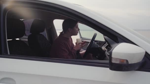 Genç bir kadın açık havada beyaz bir arabada oturuyor. — Stok video