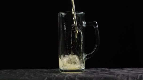 La birra leggera si sta versando nel bicchiere. IPA. Birra fredda in un bicchiere con gocce d'acqua. Birra artigianale formando schiuma da vicino. Freschezza e schiuma. Sfondo nero isolato. Birra artigianale microbirreria. — Video Stock