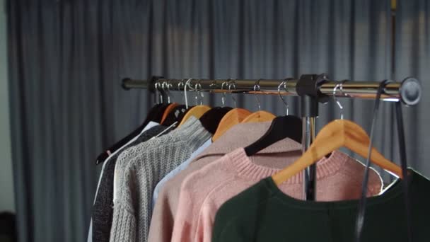 Közelkép nő vesz egy szürke pulóver egy vállfa ruhák — Stock videók